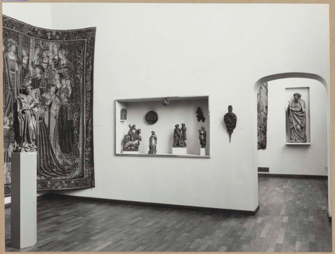 Room with tapestry, statues on a pedestal and in a display case and a passage with a view of a statue of saints in a niche, 1961 Canvas Print