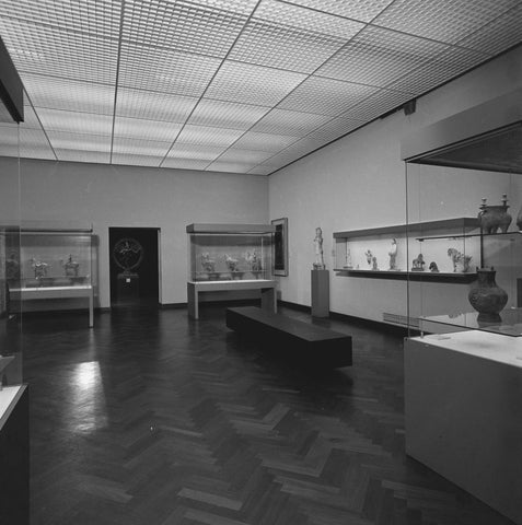 Room with objects in display cases, a statue on a pedestal and at the back a view of a room where a statue of Shiva stands, 1983 Canvas Print