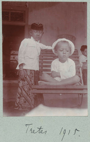 Two boys, one in traditional Javanese clothing, one sitting in a chair in a white shirt with a white hat., Frits Freerks Fountain Fz. (attributed to), c. 1914 Canvas Print