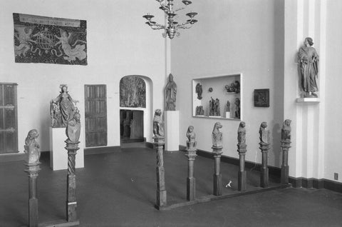 Room with tapestries, a cupboard, wooden statues on pedestals, display cases and a passage, 1952 Canvas Print