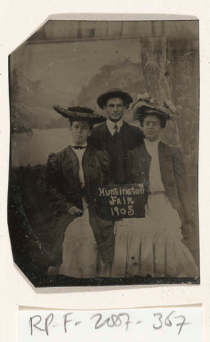 Portrait of a man and two women in front of a painted background cloth (tree, lake and mountains) and a sign with the text 'Huntington FAIR 1905', anonymous, 1905 Canvas Print