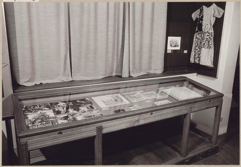 Room of the KOG with photos and drawings in a display case and a dress on the wall, c. 1975 Canvas Print