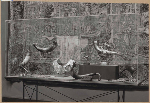 Display case with various metal objects including drinking horns, in the background a tapestry, c. 1959 Canvas Print