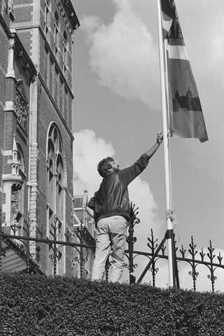 Person reaching for a flag next to a fence, 1985 Canvas Print